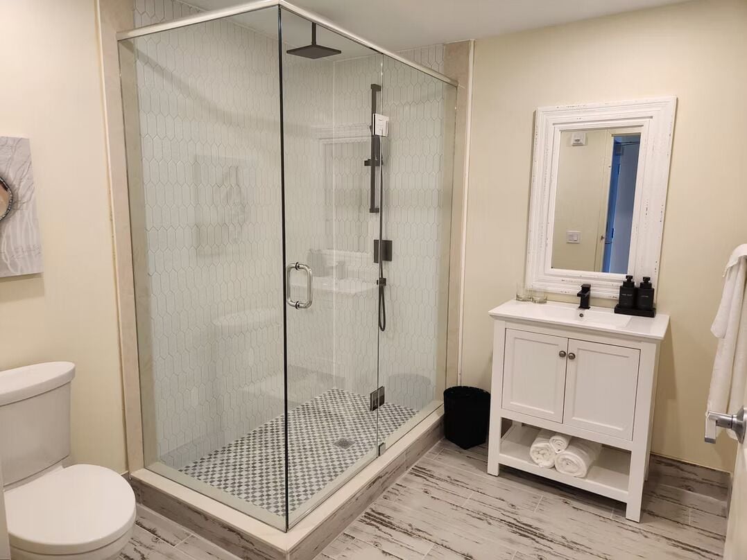 A modern bathroom with a glass-enclosed shower, a white sink, and a mirror above it.