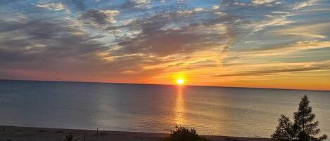 A sunset over a beach with a clear sky and calm sea.