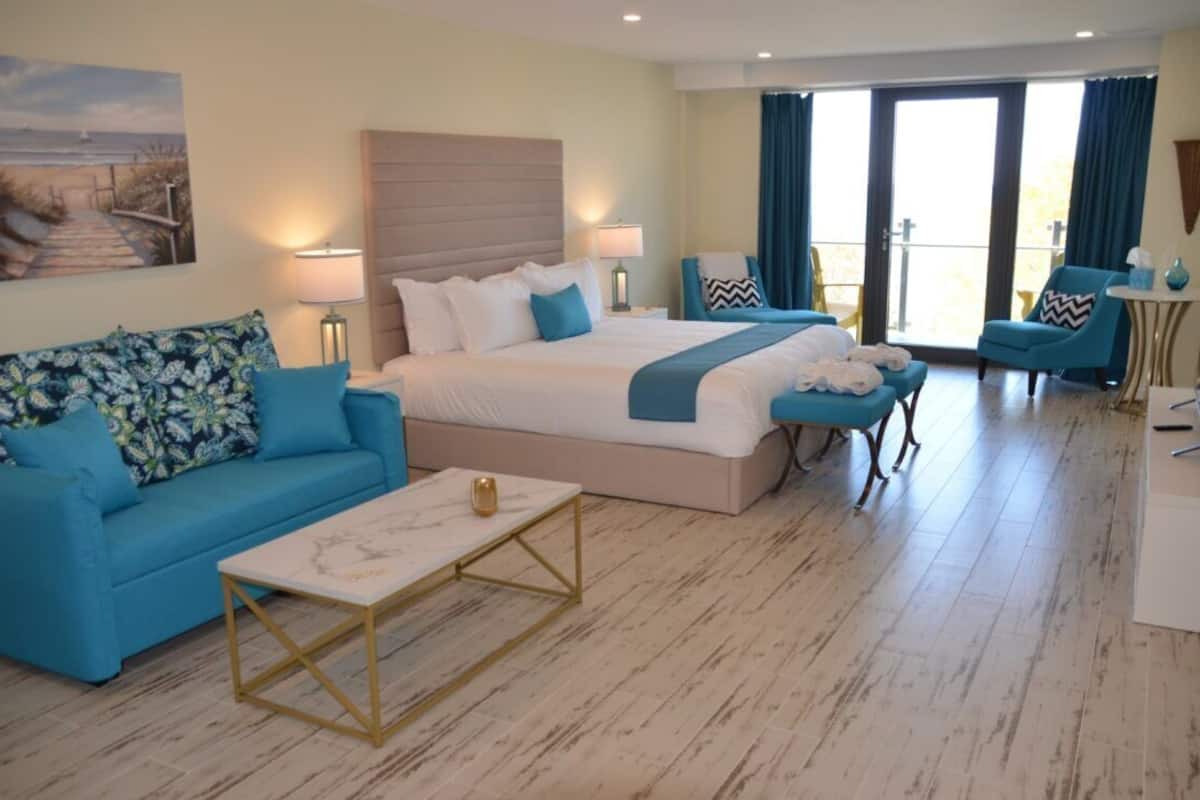 A hotel room with a bed, a sofa, a coffee table, and a chair.