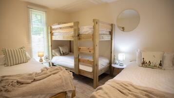 A room with two bunk beds, a round mirror, and a bedside table with a lamp.