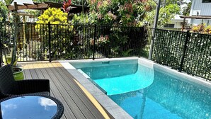 A rectangular swimming pool with a wooden deck and metal railing. - Garden Retreat with Pool - fully detached Studio (Freshwater)