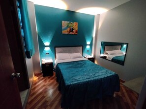 A bedroom with a bed, nightstands, a painting, and a mirror. - Hostal El Pilar (Callao)