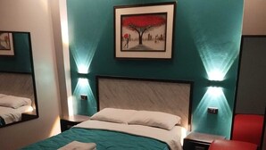 Una habitación de hotel con una cama, una silla roja y un cuadro en la pared.