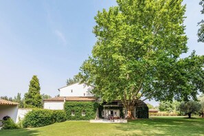 Set amidst lush greenery, this serene property features a traditional single-story building with a white facade and terracotta roof.