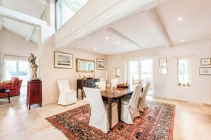 Enjoy a comfortable dining experience in this inviting space with a high ceiling, exposed beams, and elegant artwork.