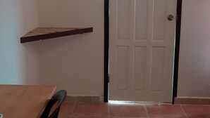 A room with a tiled floor, a wooden table with chairs, and a white door with a dark frame. - Belize Sea Reef Inn (Caye Caulker)