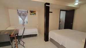 A small, clean room with a bed, a desk, and a chair. There is a window with a view of palm trees and a painting on the wall. - Belize Sea Reef Inn (Caye Caulker)