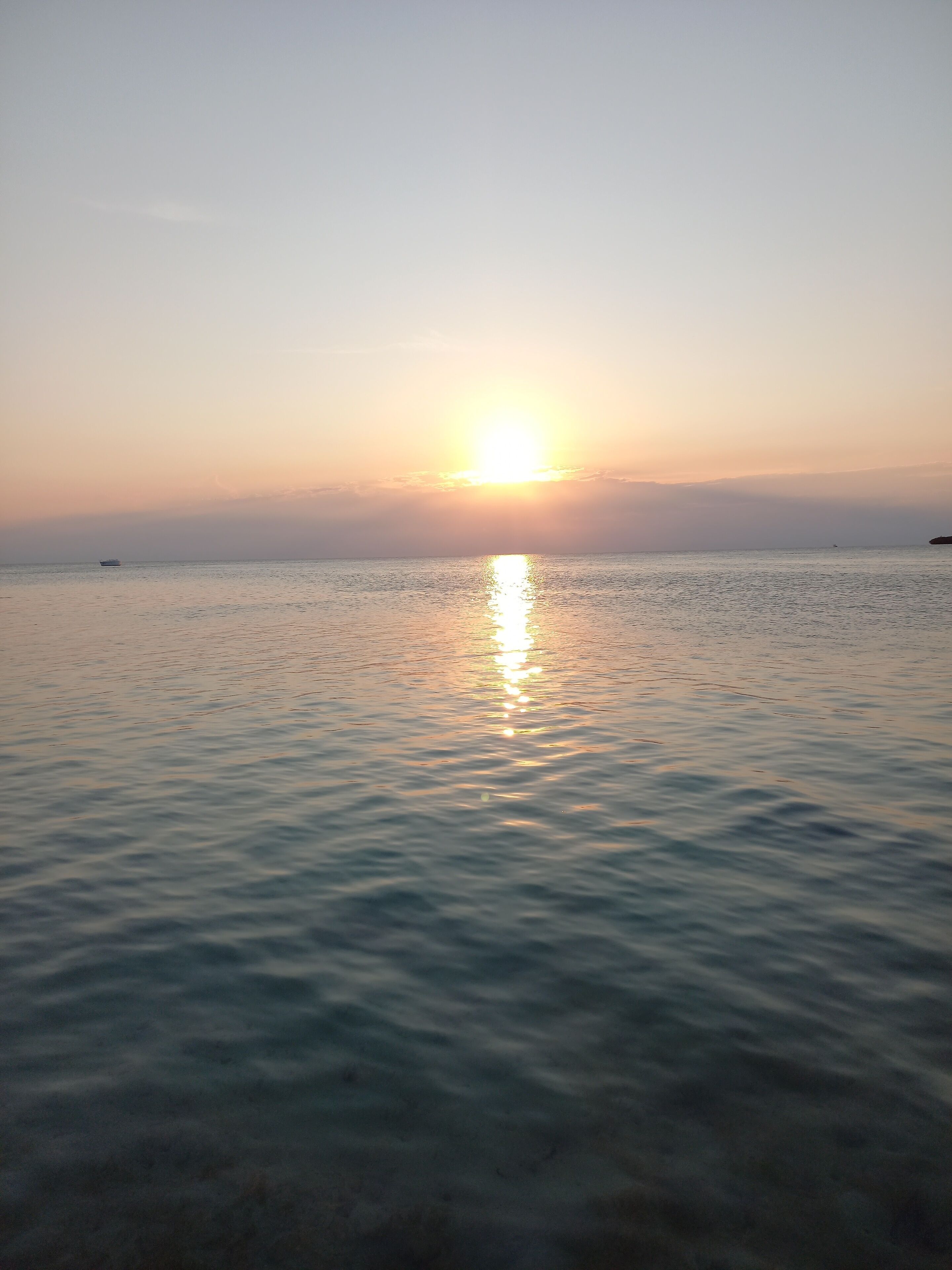 Ruhige See bei Sonnenuntergang, ein Boot in der Ferne.