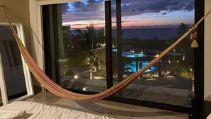 Un'amaca legata a una finestra con vista su una piscina e sulla zona resort al crepuscolo.
