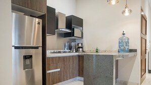 A modern kitchen with a stainless steel refrigerator, a built-in microwave, a coffee maker, and a water dispenser.