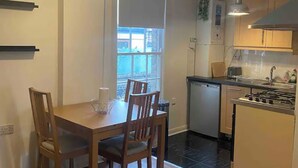 A compact kitchen with a dining table, chairs, and a small island. - Cosy 2 Bedroom Gem near Oxford Street (London)
