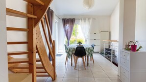 A modern kitchen with a wooden staircase, a dining area with a table and chairs, and a view of the outdoors. - Parenthèse Tourangelle - Families & Business (Tours)