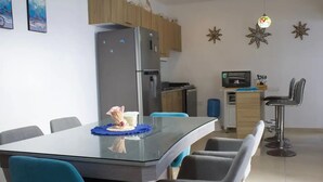 A modern kitchen with a refrigerator, oven, and microwave. There is a dining table with chairs and a small island with a sink. - Casa Del Mar.  (Chelem)