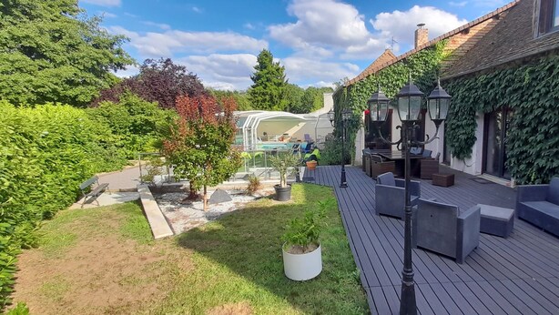 A wooden deck with outdoor seating, a pool, and a house with ivy-covered walls.