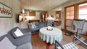A cozy living room with a grey sofa, a round table with a patterned tablecloth, and a wooden floor. - Nice home in Annerstad with WiFi (Annerstad)