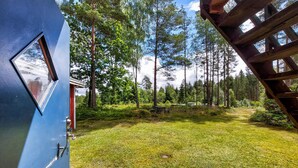 A blue door with a window, a wooden deck, and a grassy yard with trees in the background. - Nice home in Annerstad with WiFi (Annerstad)