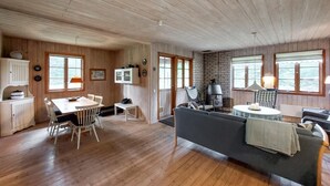 A cozy cabin interior with a dining area, a sofa, and a fireplace. - Nice home in Annerstad with WiFi (Annerstad)