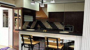 Une cuisine moderne dotée d’un îlot central, de luminaires suspendus et de tabourets de bar.