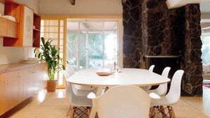 Zona pranzo moderna con soffitto in legno, parete in pietra e un'ampia finestra.