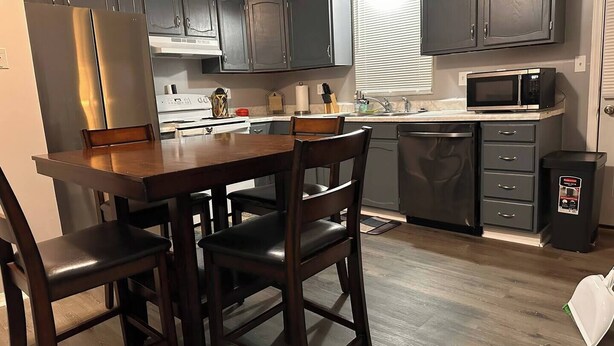 A kitchen with dark cabinets, a stainless steel refrigerator, a microwave, and a dishwasher. - ~A Home Away From Home~Sleeps 8~

 (Columbia)