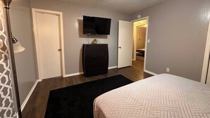 A bedroom with a bed, a dresser, a TV on the wall, and a door leading to another room. - ~A Home Away From Home~Sleeps 8~

 (Columbia)