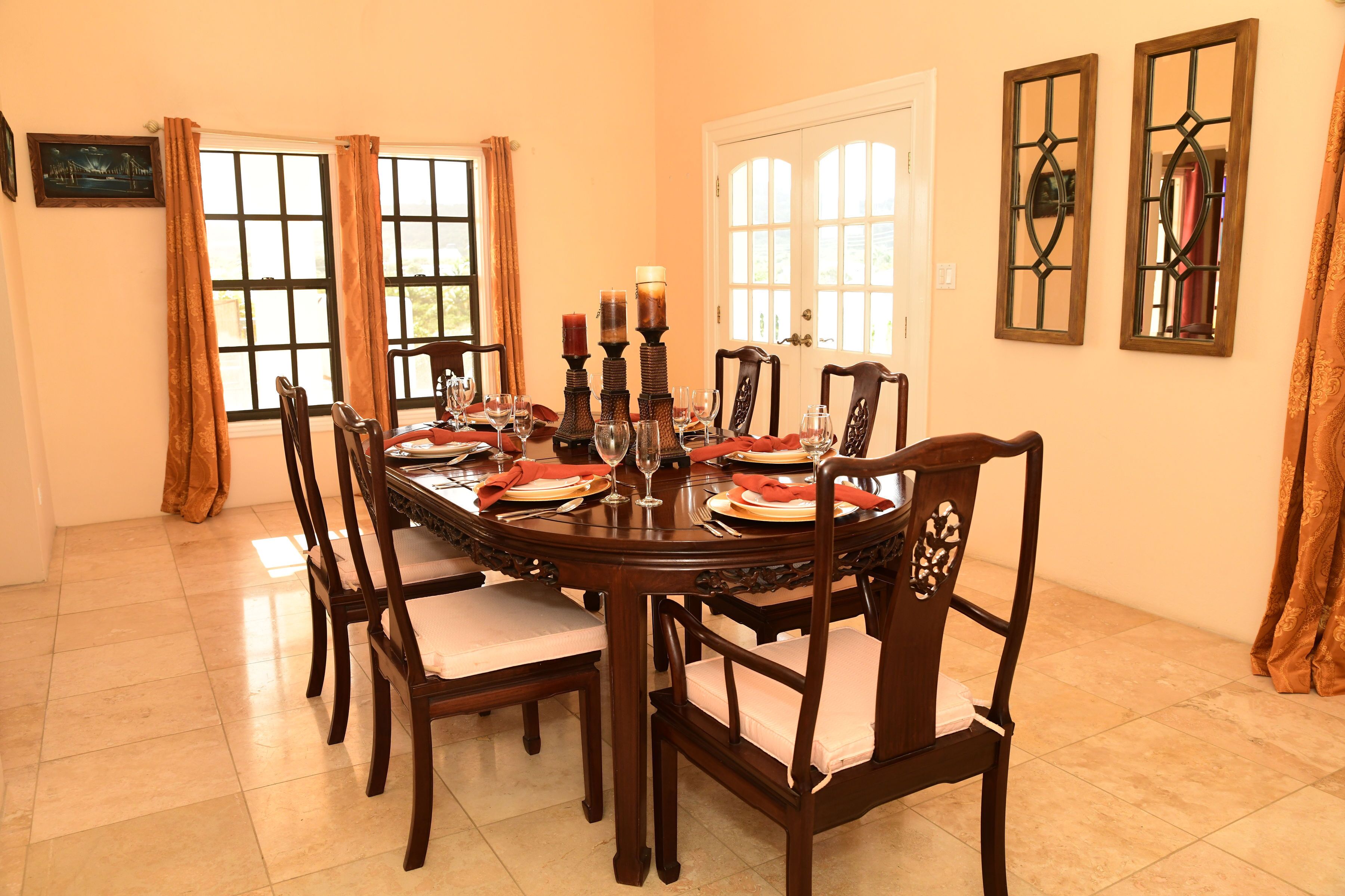 Comedor con una mesa redonda dispuesta para seis personas, rodeada de sillas de madera con asientos acolchados.