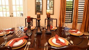 Una mesa de comedor dispuesta para una comida, con sillas, velas y cristalería.