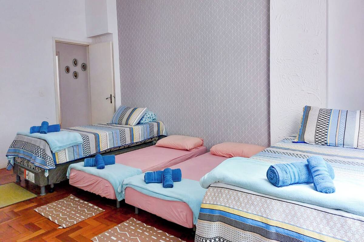 Un dormitorio con dos camas individuales, cada una con una colcha y almohadas estampadas, un ventanal con vistas y una puerta con pomo.