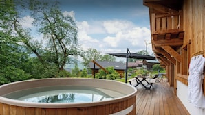 Una terraza de madera con un jacuzzi, un porche de madera y una bata blanca colgada en la pared.