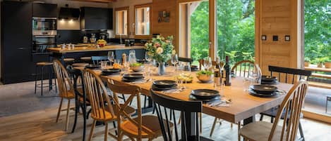 Una cocina moderna con una isla central, ventanas amplias y un comedor preparado para seis personas.