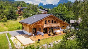 Una cabaña de madera con balcón, mobiliario exterior y vistas a las montañas.