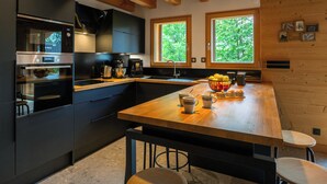 Una cocina moderna con armarios oscuros, una isla de madera y un ventanal amplio.