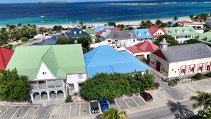 An aerial view of a coastal town with colorful buildings, a beach, and a clear view of the ocean. - Orient Parc - the best location (Saint martin)