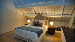 A bedroom with a large bed, two bedside tables, a nightstand, a ceiling fan, and a skylight. - Orient Parc - the best location (Saint martin)