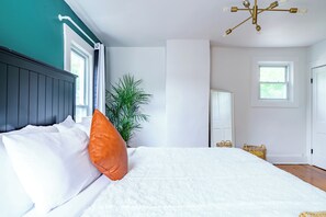 A bedroom with a bed, a potted plant, a mirror, and a chandelier. - Jungle House Urban Lofts – Arena District & Short North (Columbus)