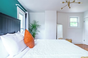 Ein Schlafzimmer mit Bett, Topfpflanze, Spiegel und einer Chandelier.