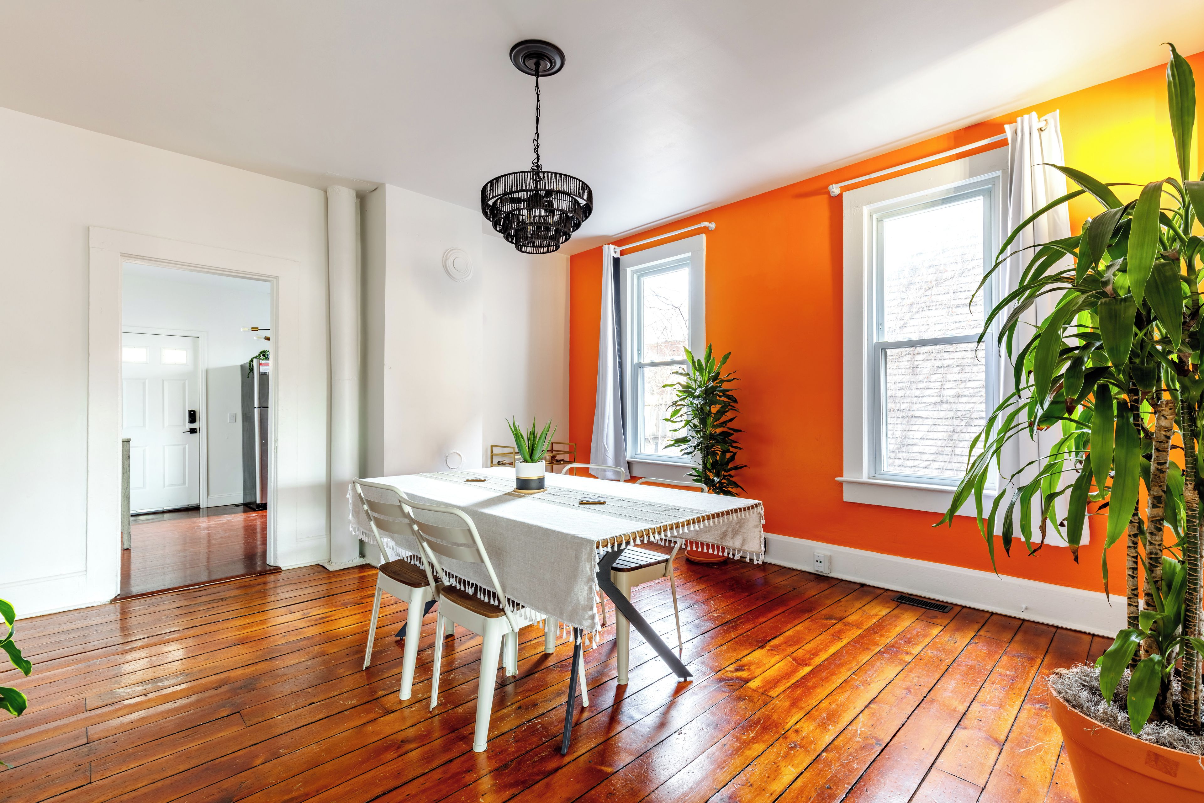 A dining area with a table, chairs, and a hanging light fixture.