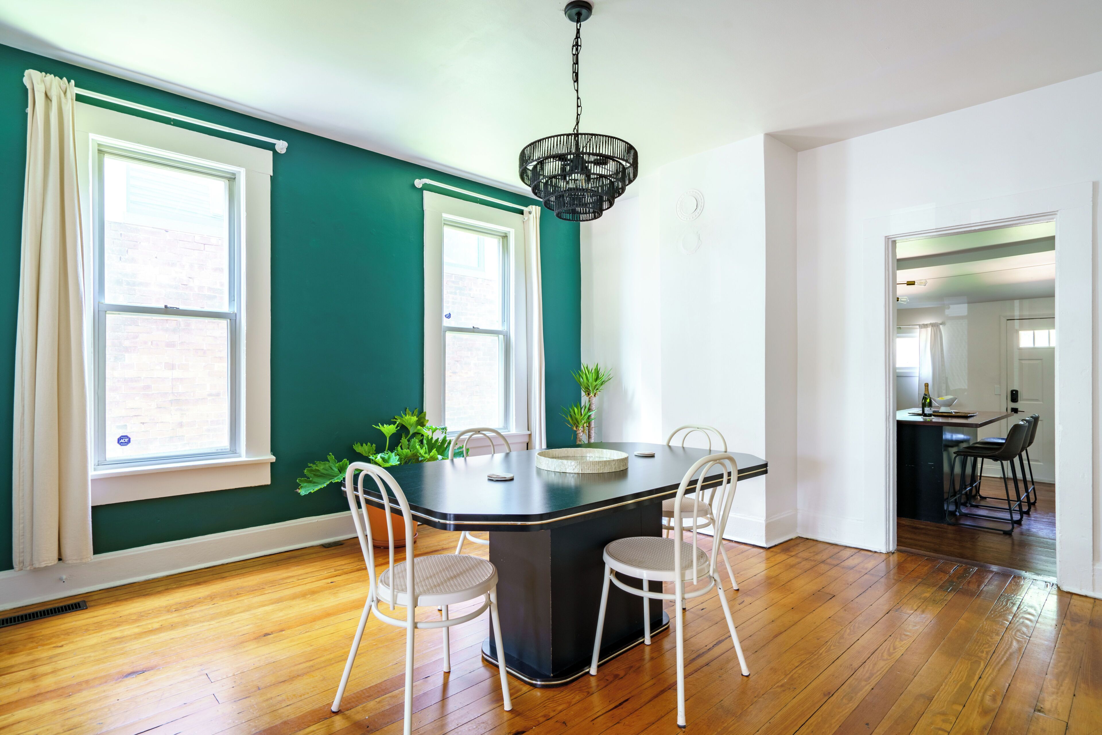 A dining area with a black table, white chairs, and a hanging light fixture.
