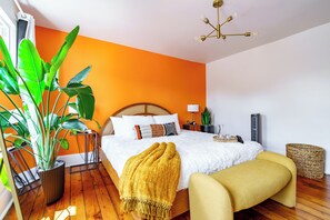 Une chambre à coucher comprenant un lit, une table de chevet, une lampe, une plante en pot et un banc.