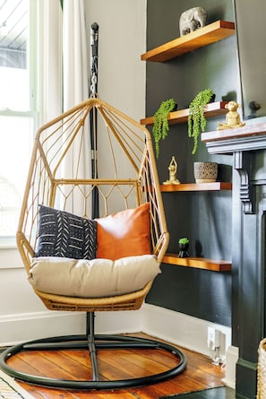 Una habitación con una silla colgante, repisas de madera y una chimenea.
