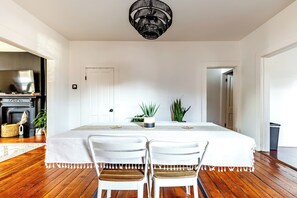 A dining area with a table, chairs, a chandelier, and a fireplace. - Jungle House Urban Lofts – Arena District & Short North (Columbus)
