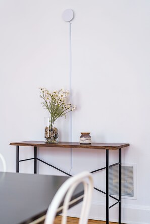 A minimalist room with a wooden table, a vase with flowers, and a small decorative jar. - Jungle House Urban Lofts – Arena District & Short North (Columbus)