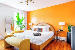 Une chambre à coucher moderne avec un lit en bois, deux tables de chevet avec des lampes, une grande fenêtre et une plante.