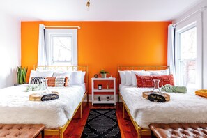 A room with two beds, a white fluffy rug, a small white nightstand, and a window with curtains. - Jungle House Urban Lofts – Arena District & Short North (Columbus)