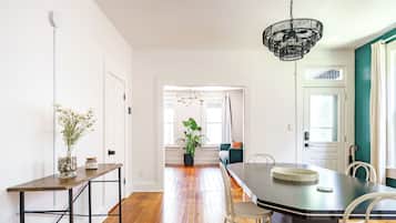A dining area with a wooden table, chairs, a chandelier, and a potted plant.