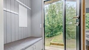 Een kamer met een bank, een schuifdeur naar een tuin, en een witte muur met een stopcontact.
