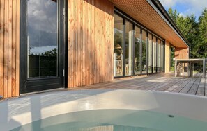 Ein modernes Gebäude mit Holzfassade, großen Schiebegläsern und einer Holzterrasse.