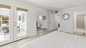 Un dormitorio espacioso con una cama grande, un vestidor y vistas del patio exterior.