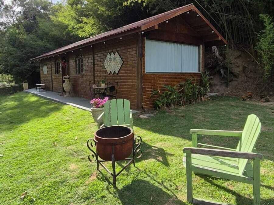 Una cabaña rústica con fachada de ladrillo, un porche con mobiliario exterior y un ventanal grande.