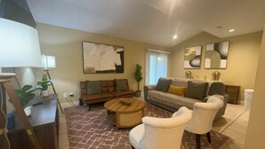 A living room with a sofa, two white armchairs, a coffee table, and a lamp. - Stylish 4-bedroom, 3 Bath Townhome in Valdosta (Valdosta)